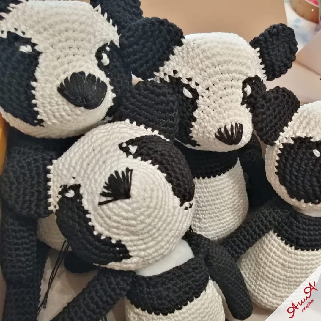 A collection of black and white crocheted panda bears with hand-stitched facial features.