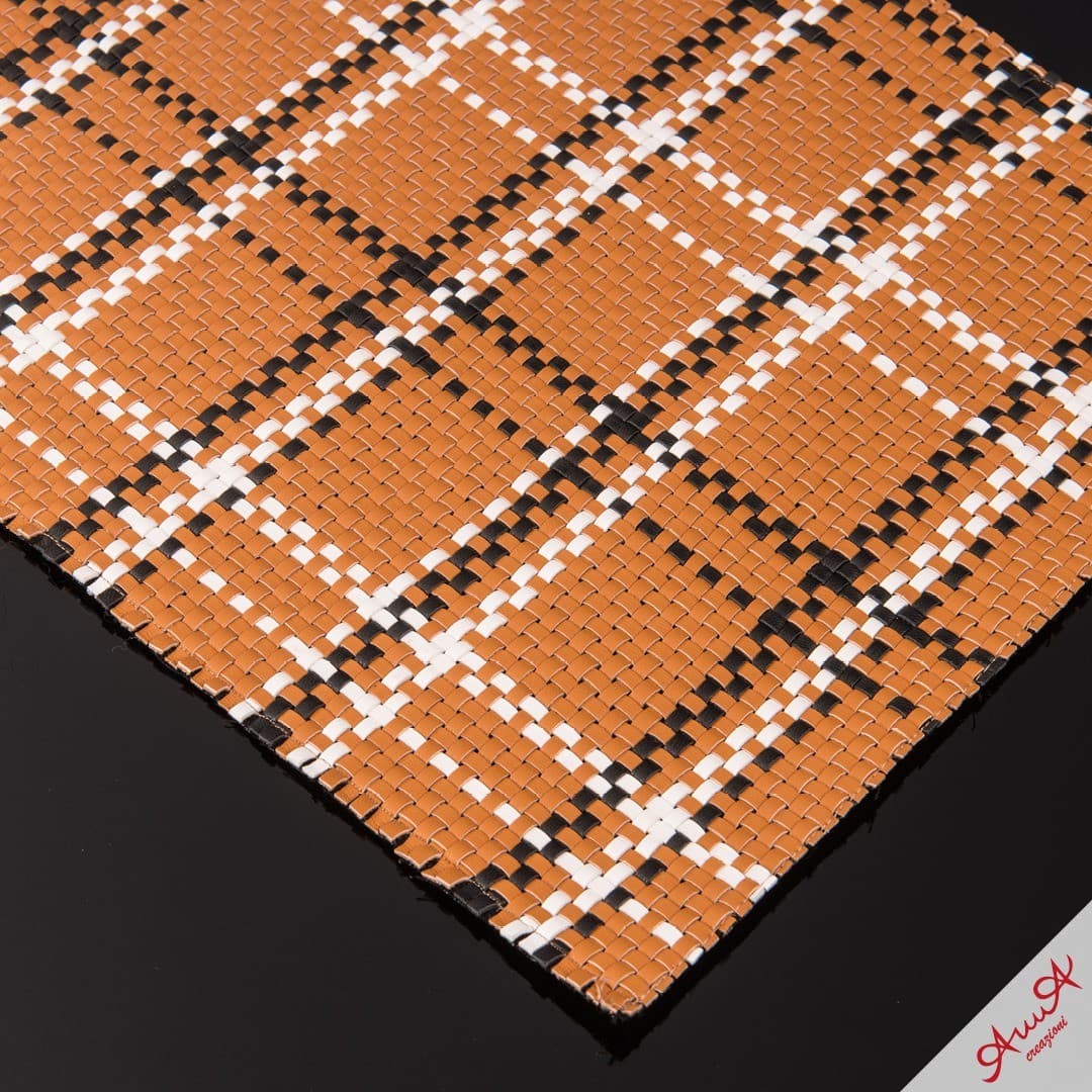 Tan woven leather material with a black and white plaid pattern on black surface.